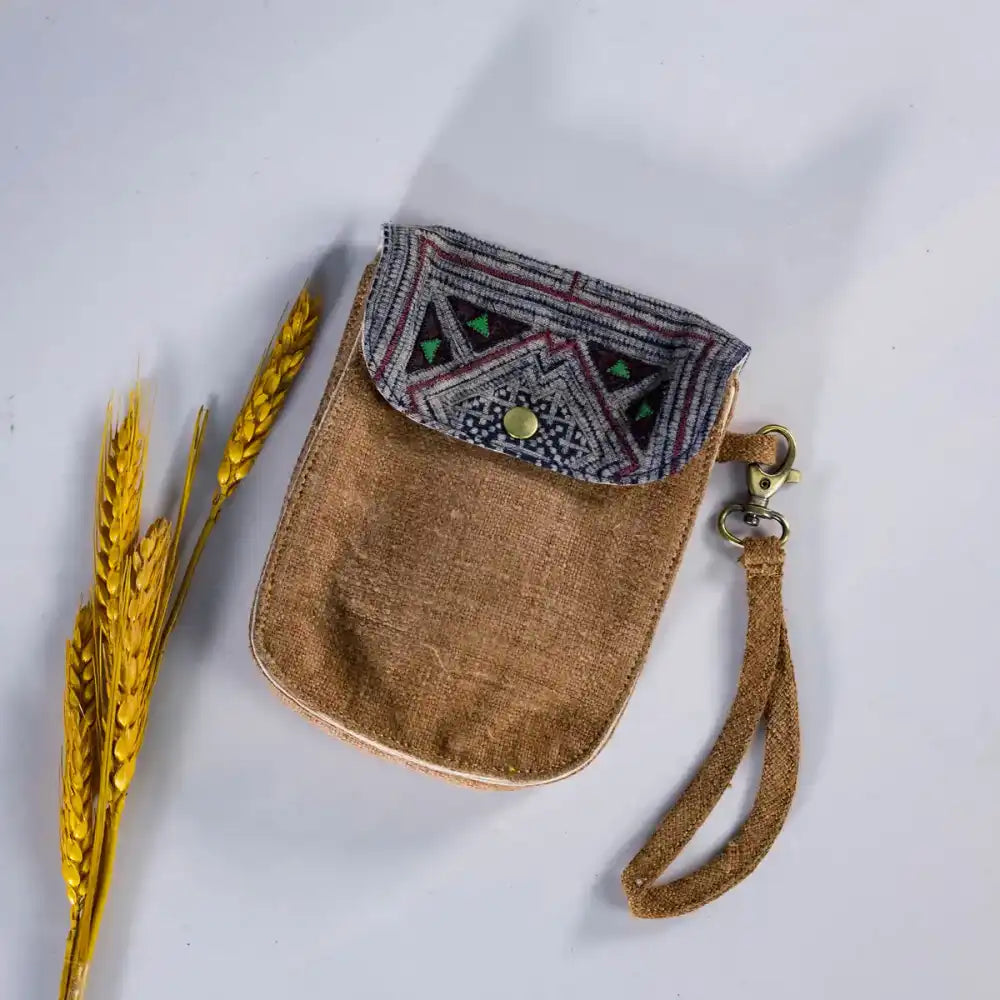 Flatlay of brown hemp flip phone belt bag with vintage patch, handmade eco-friendly accessory.