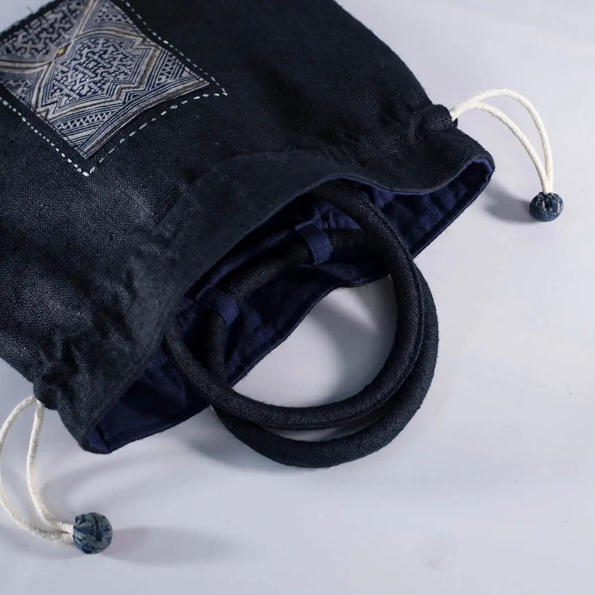 Open view of black hemp bucket bag showing cotton lining and vintage H’Mong patch