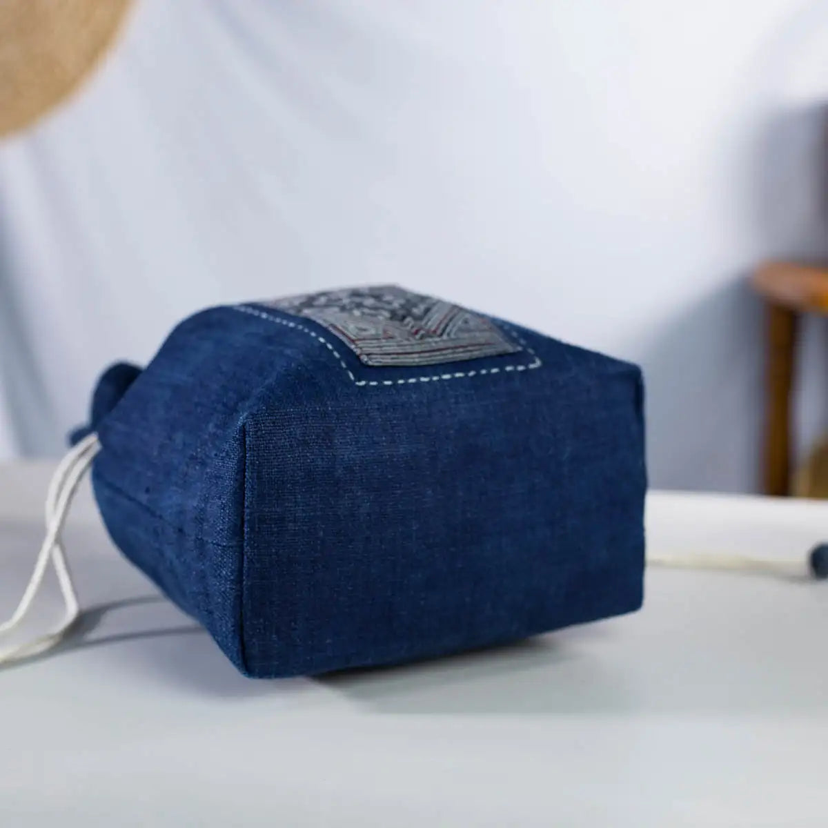 Side view of indigo hemp bucket bag, handcrafted sustainable design with H’mong fabric detail.