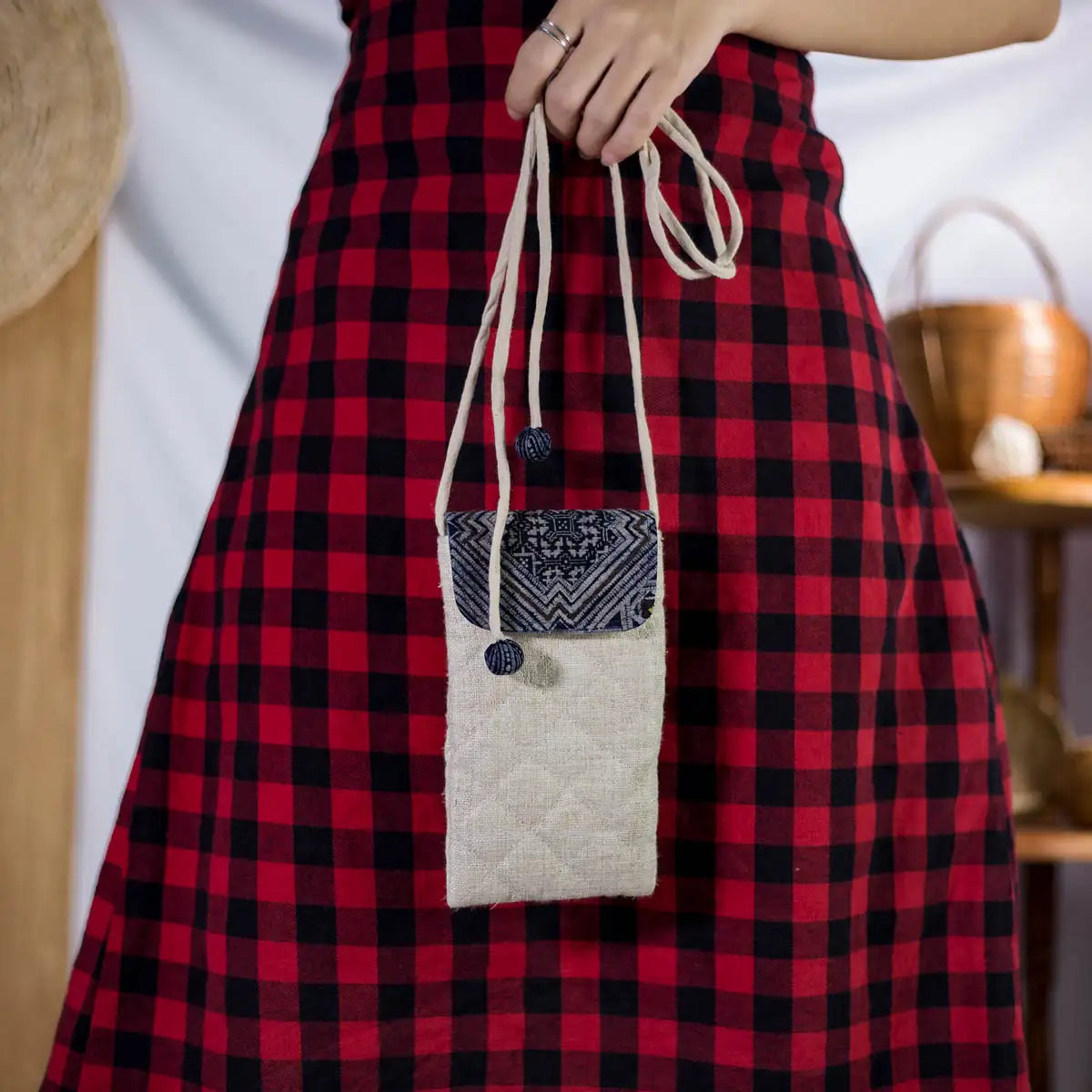 Natural hemp drawstring bucket bag with H’Mong patch, front view held by model