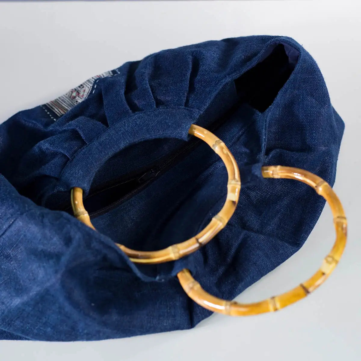 Close-up of indigo hemp bamboo handle bag with authentic H’mong patch, sustainable design.