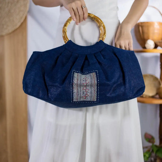 Indigo hemp handbag with round bamboo handles and H’mong patch, artisan-made eco-friendly fashion.