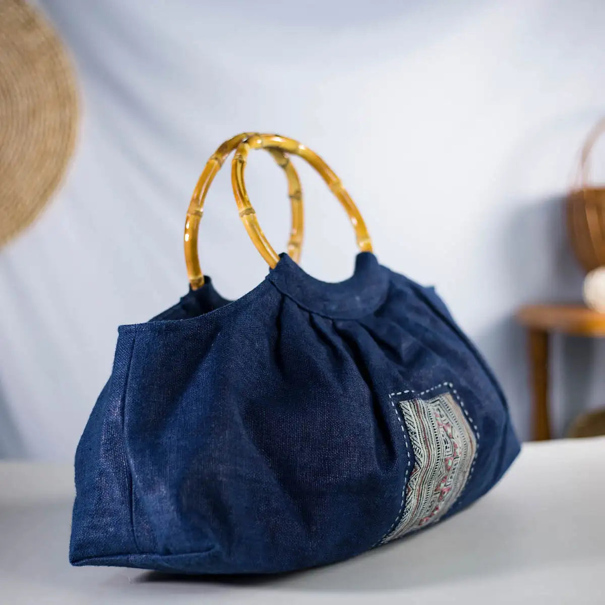 Side view of indigo hemp handbag with bamboo handles and H’mong patch, artisan-made design.