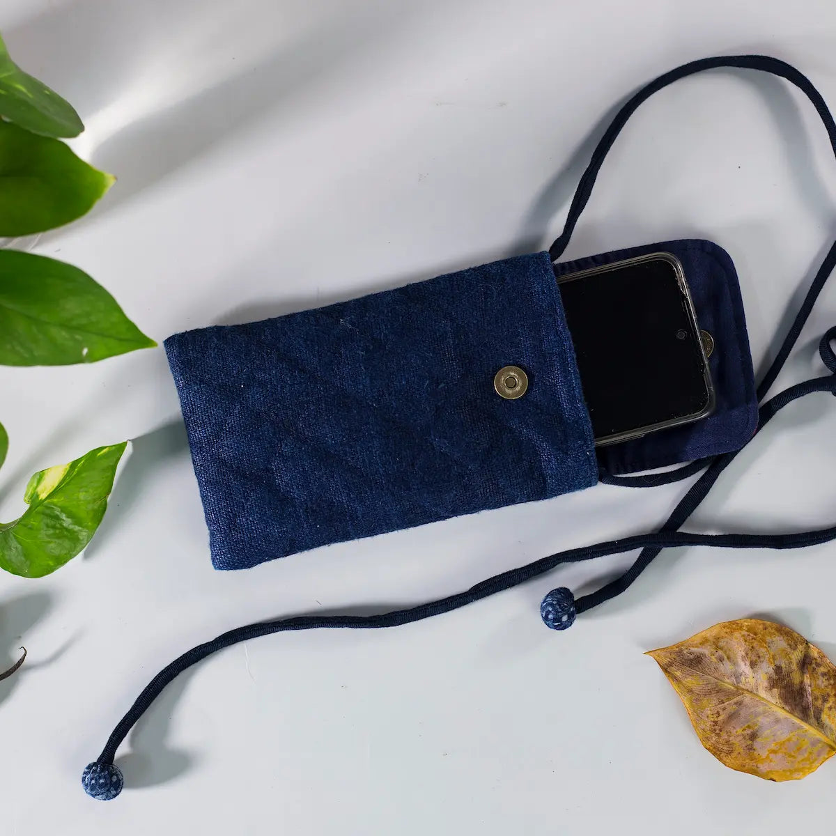 Closed view of indigo hemp mobilväska phone bag with strap and H’mong patch, sustainable design.