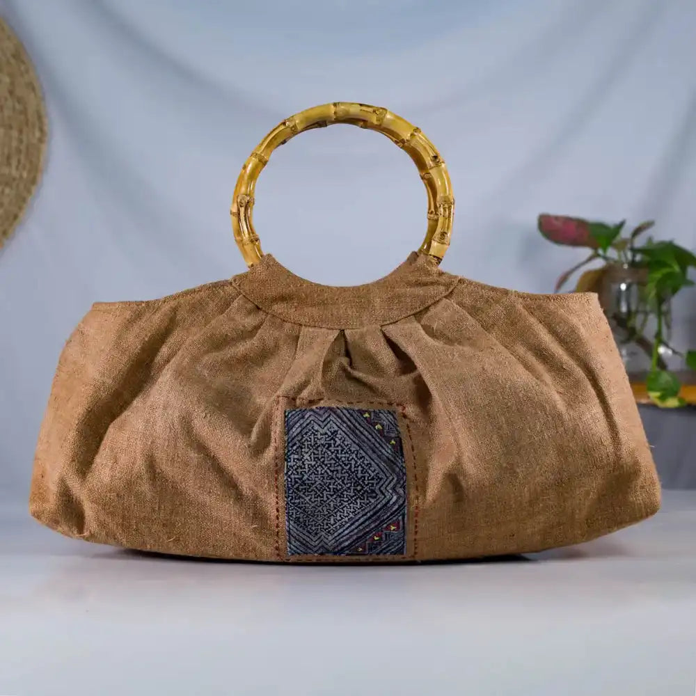 Front view of natural brown hemp bucket bag with bamboo handles and H’Mong patch