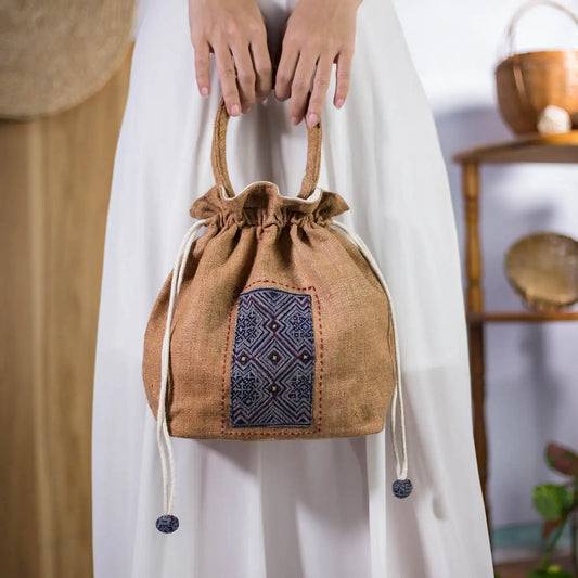 Model holding natural hemp bucket bag with round fabric handles and H’Mong patch