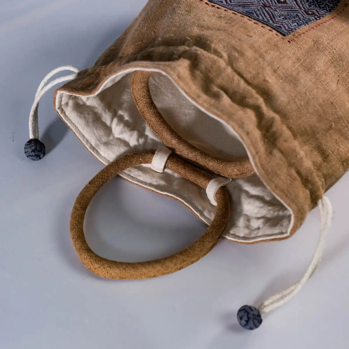 Open natural hemp bucket bag with H’Mong patch, showing spacious interior and drawstring closure