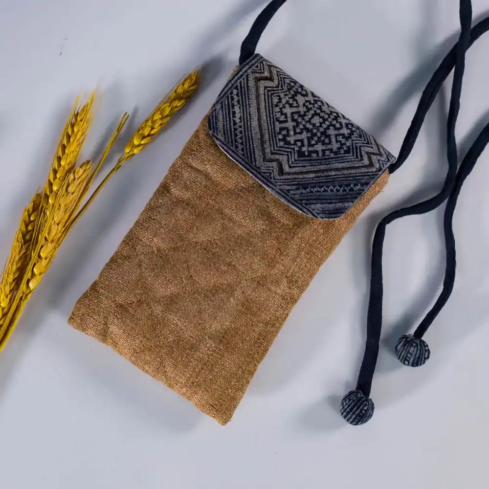 Flatlay of natural brown hemp phone bag with H’Mong patch, eco-friendly handmade accessory.