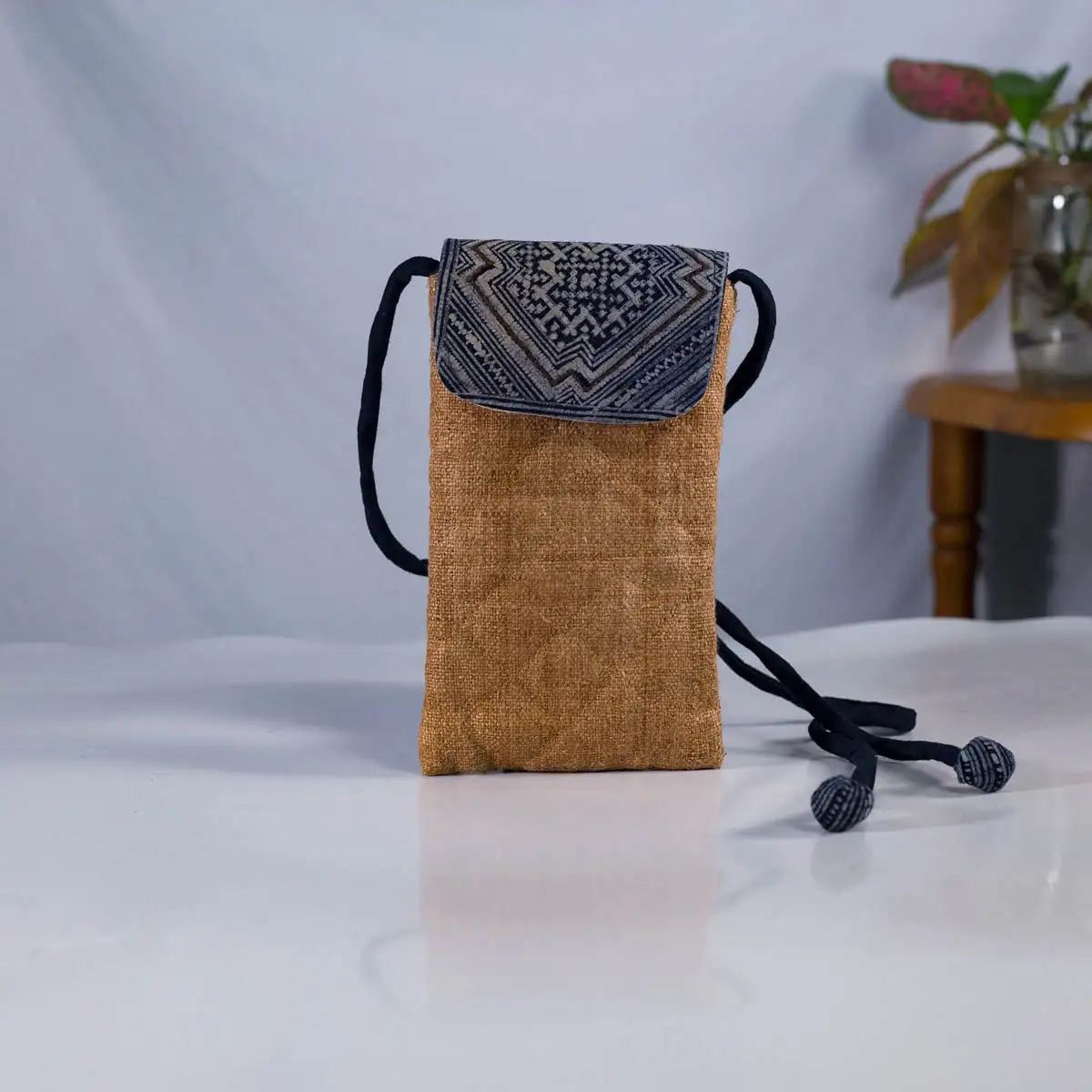 Front view of natural brown hemp phone bag with H’Mong patch and adjustable strap, handmade design.