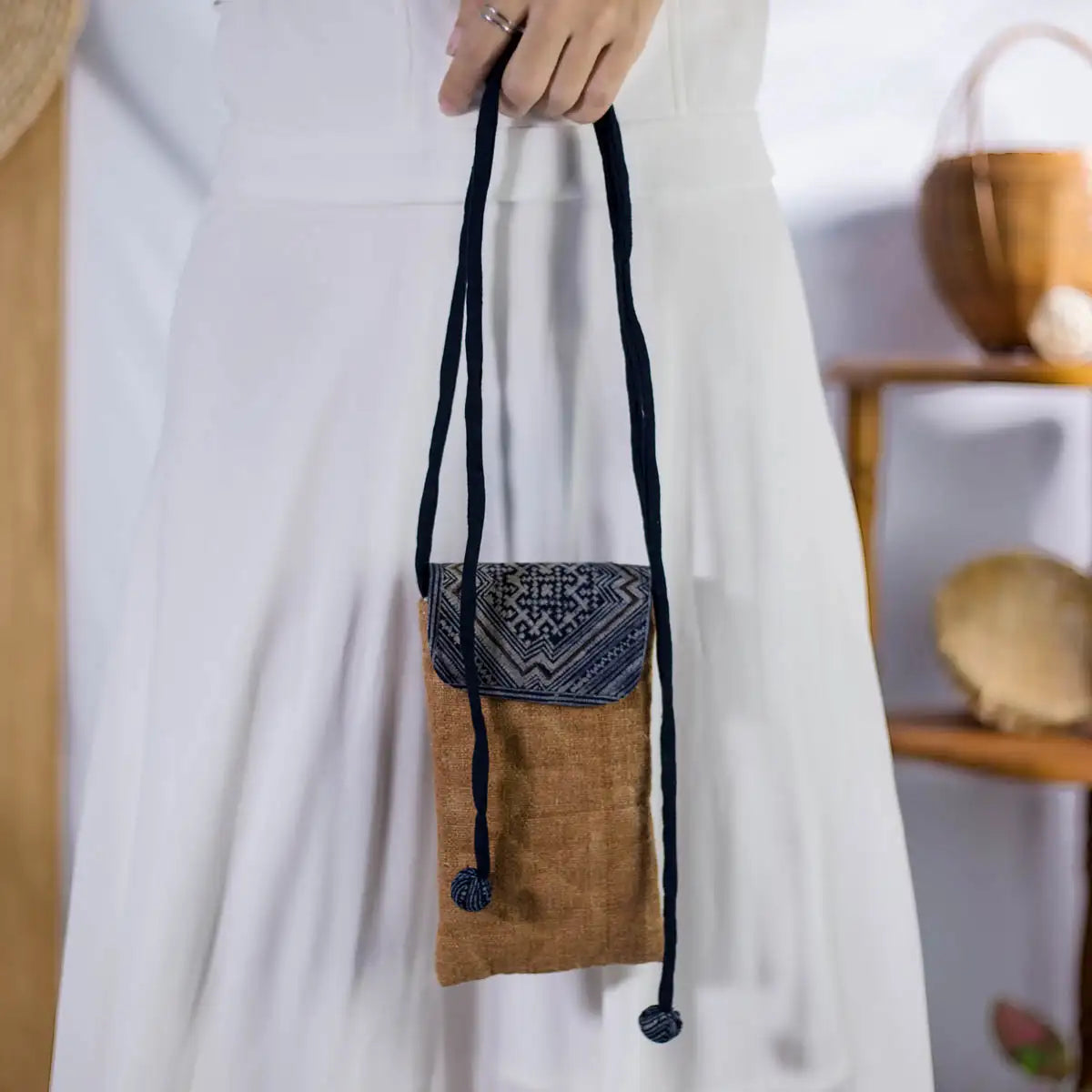 Model carrying natural brown hemp phone bag with H’Mong patch, eco-friendly handmade accessory.