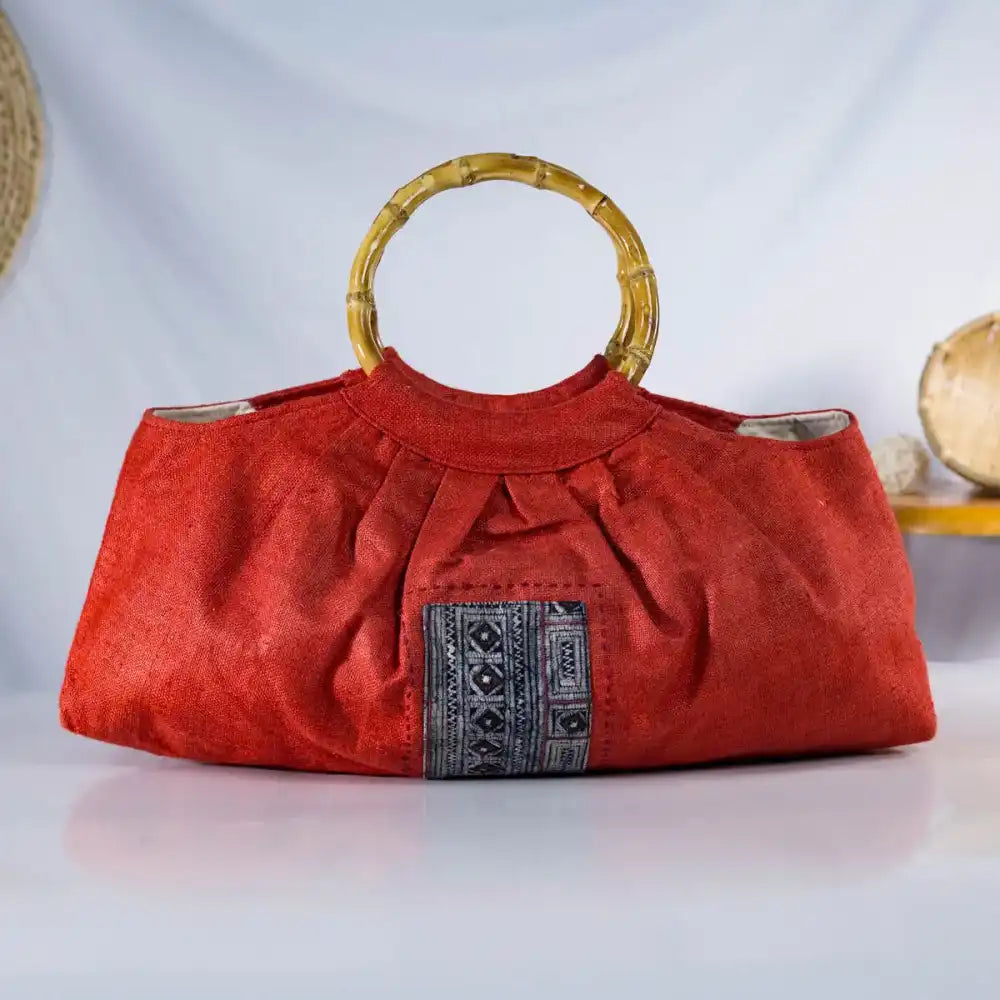 Front view of red hemp handbag with bamboo handles and H’mong patch, eco-friendly handmade fashion.