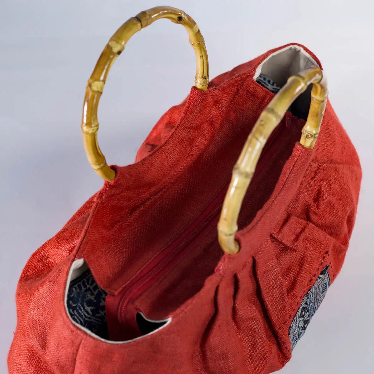 Detail of red hemp handbag with sturdy bamboo handles and handmade H’mong patchwork accent.