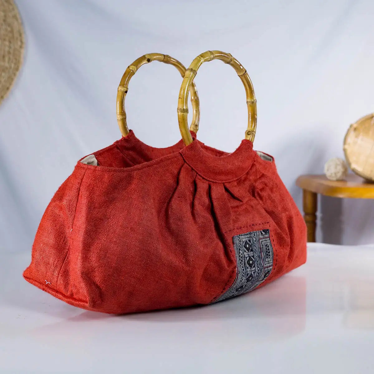 Side view of red hemp handbag with bamboo handles and H’mong fabric patch, sustainable bag.