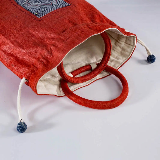 Detail of red hemp bucket bag with sturdy handles and H’mong fabric patchwork accent.