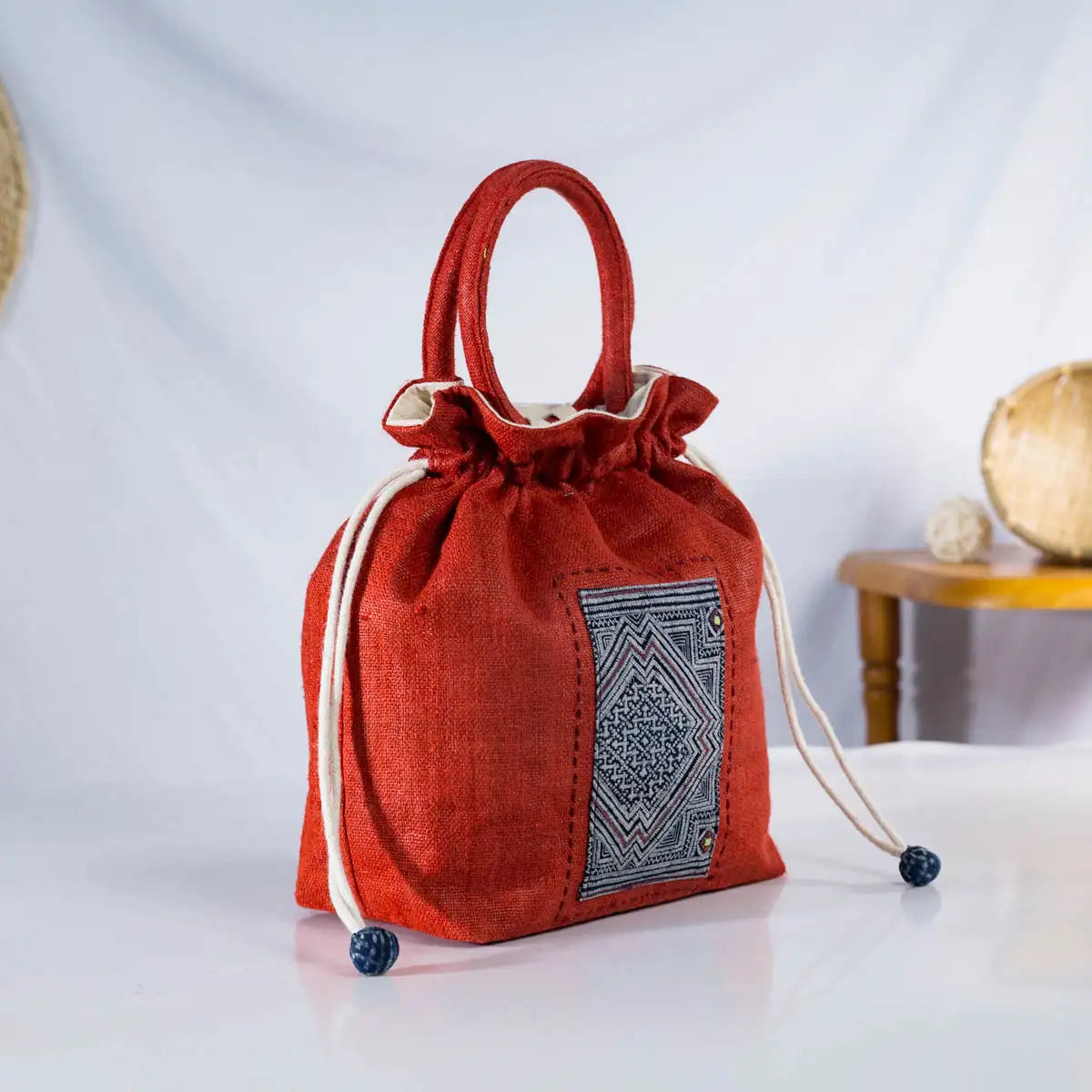 Front view of red hemp bucket bag with round handles and H’mong patch, eco-friendly handmade fashion