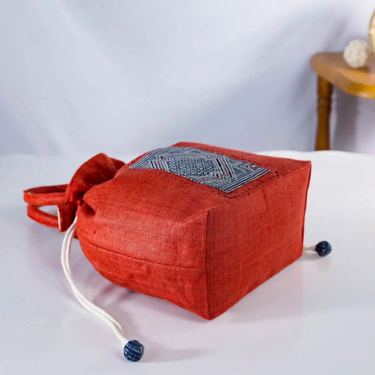 Side view of red hemp bucket bag with H’mong patch, artisan-crafted eco-friendly handbag.