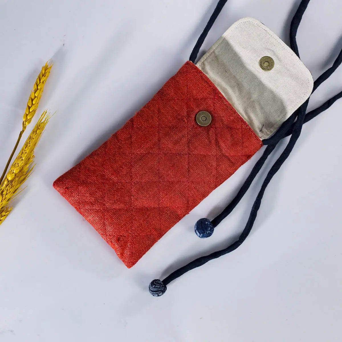 Red hemp mobilväska phone bag with strap, shown with phone inside, artisan-made eco-friendly design.