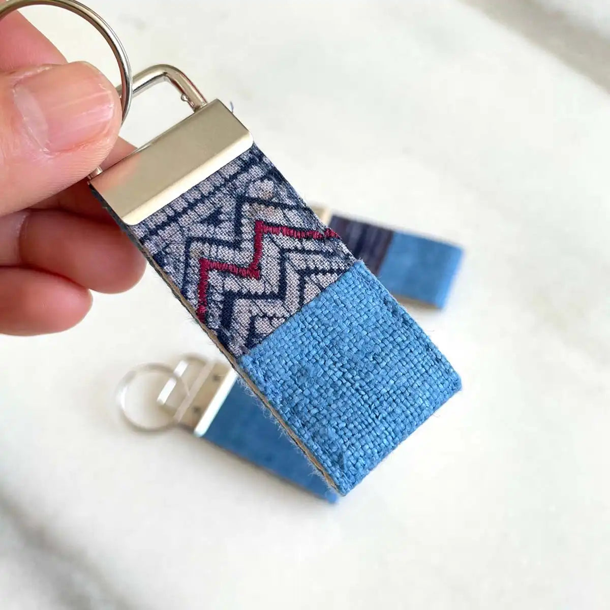 Vindigo keychain blue embroidered detail close-up in hand