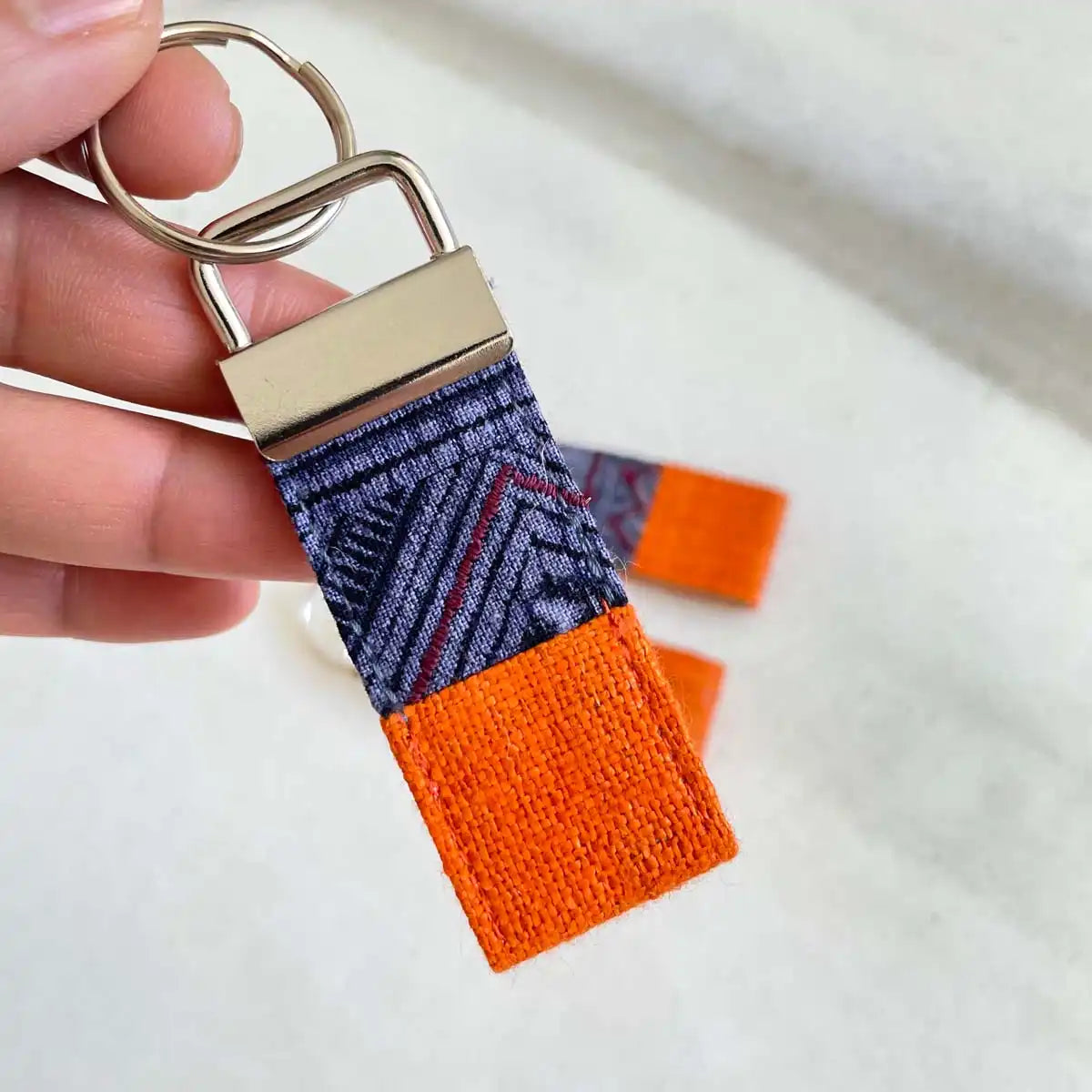 Vindigo keychain orange embroidered close detail in hand
