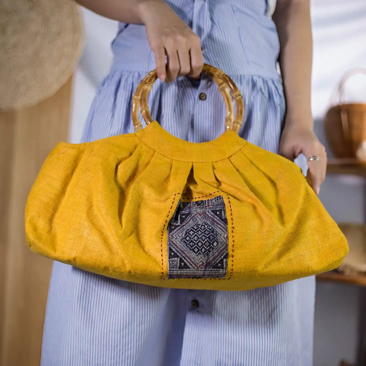 Yellow hemp handbag with bamboo handle, held by model, artisan handmade from Vietnam.