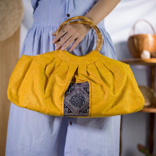 Lifestyle shot of handmade yellow hemp handbag with bamboo handle, eco-friendly artisanal fashion.