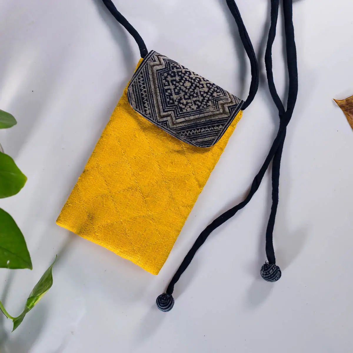 Flat lay of yellow hemp phone crossbody bag with vintage embroidered patch