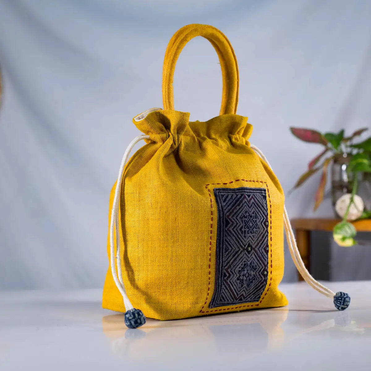 Yellow hemp drawstring bucket bag with embroidery detail and round handle by Vindigo