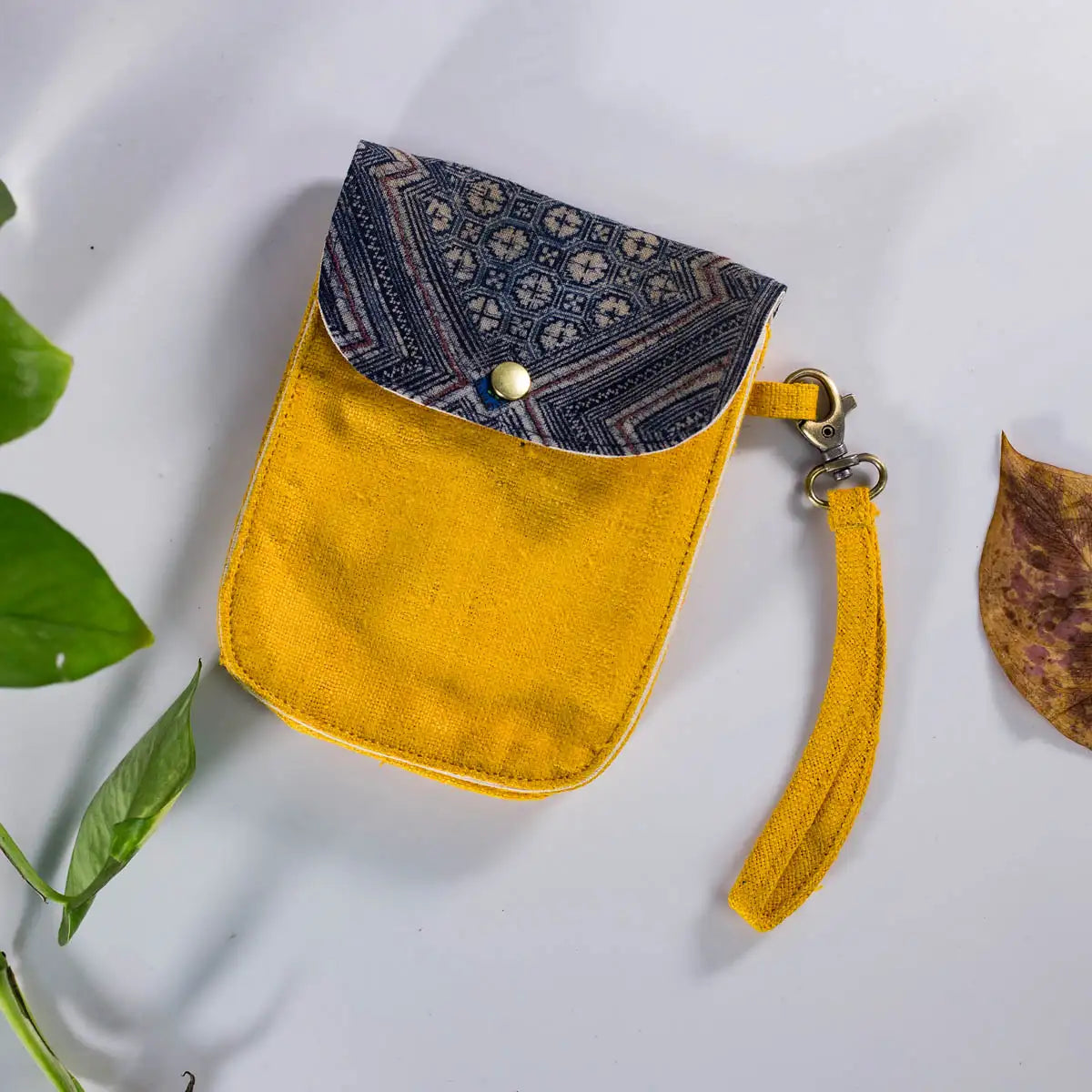 Flatlay of yellow hemp flip phone belt bag with H’Mong patch, handmade eco-friendly.